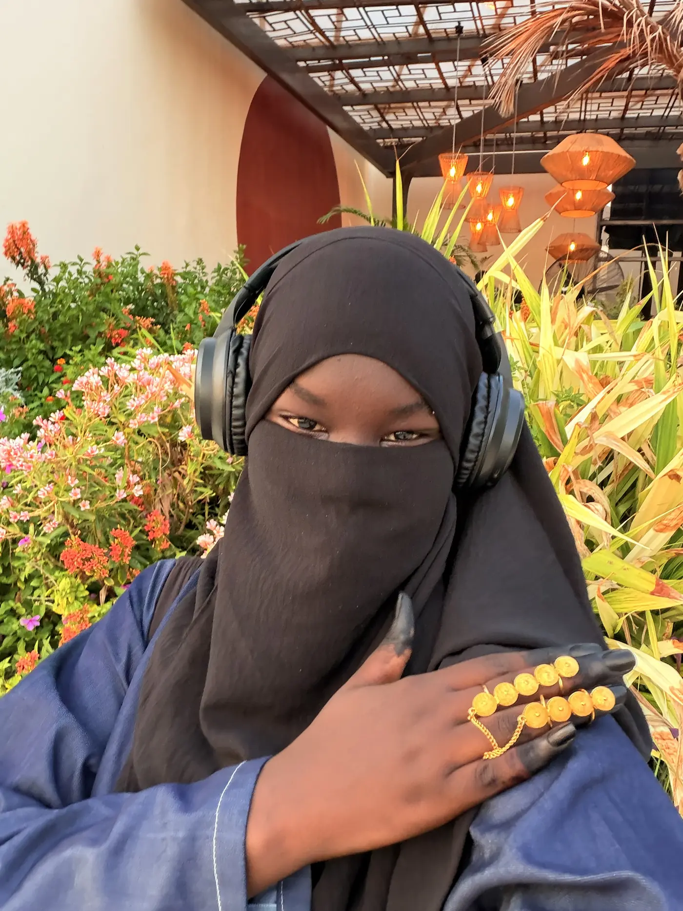Penda Carlol au casque audio dans un jardin fleuri, lumière de fin de journée