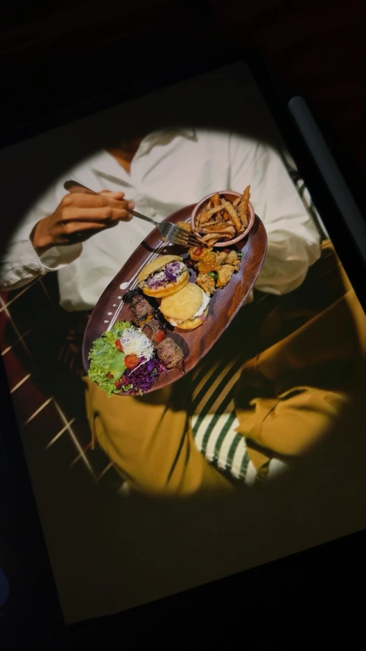 Tablette affichant une photo culinaire posée sur un plateau en bois