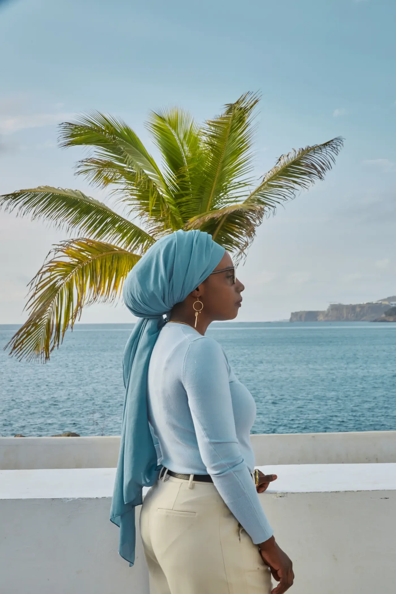 Portrait de la cliente de profil au bord de la mer, foulard bleu et palmier en arrière-plan