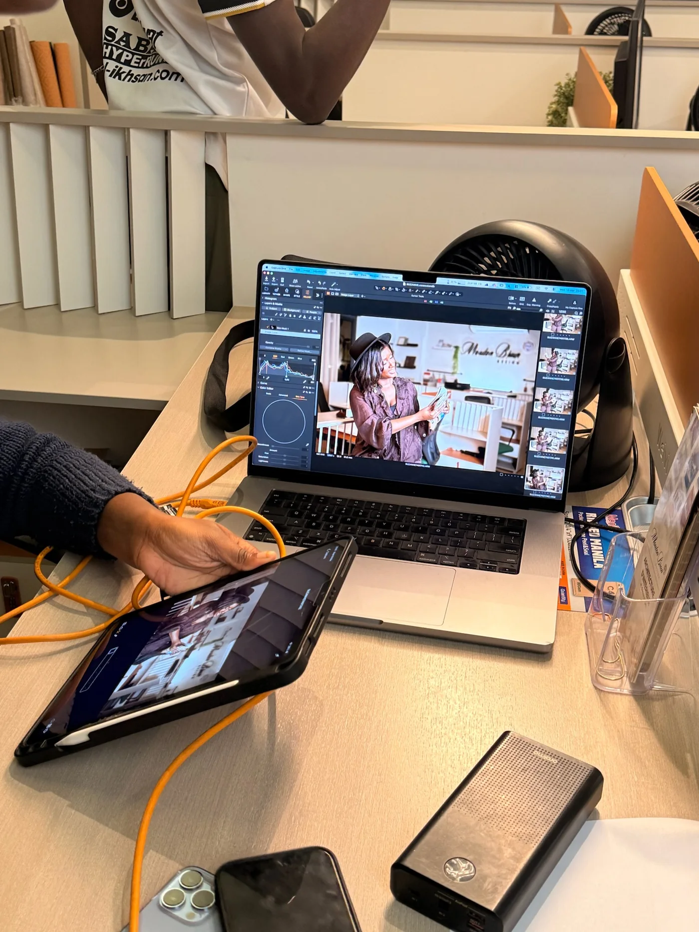 Séance de retouche en cours sur un ordinateur portable, tablette et câbles sur un bureau clair