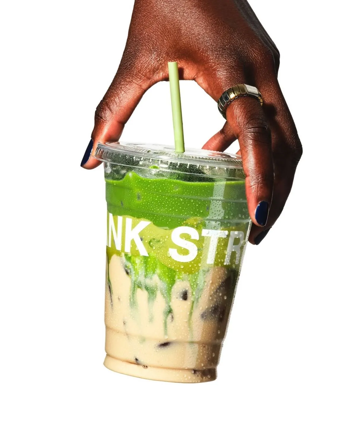 Main tenant un gobelet de matcha latté glacé, fond clair
